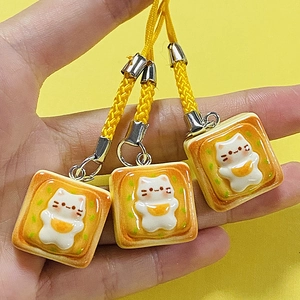 Cute resin cat toast keychain with yellow braided strap and cartoon fried egg design