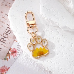 Cat paw keychain with real yellow sunflower resin pendant on white textured stone background
