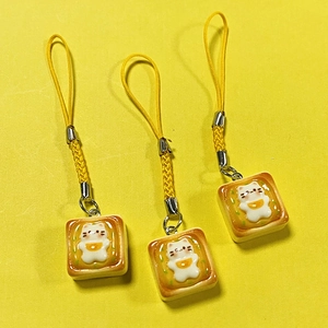 Detailed view of three cute resin cat toast charms with yellow braided mobile phone lanyards