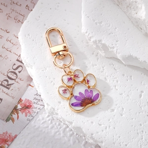 Cat paw keychain with purple dried flowers in resin and gold metal frame on stone