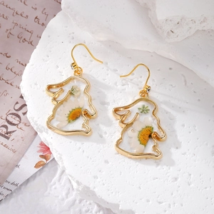 Vue macro détaillée de boucles d'oreilles lapin dorées avec de vraies fleurs de narcisse