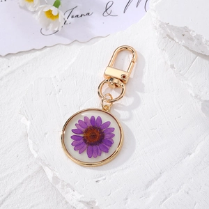 Detailed macro view of a purple daisy dried flower preserved in a resin pendant keychain