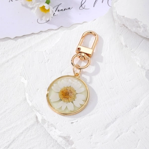 Detailed macro view of a luminous round resin keychain with a real white daisy flower inside