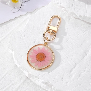 Luminous round resin keychain with pink dried daisy flower and golden metal clasp