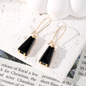 Elegant gold earrings with long trapezoid black crystal glass drops on white background