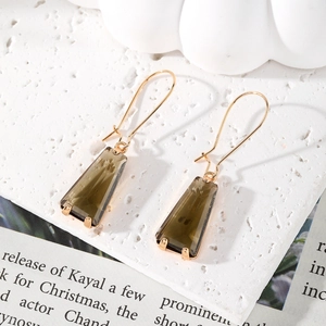 Close-up of geometric trapezoid drop earrings with smoky gray crystal and gold hooks