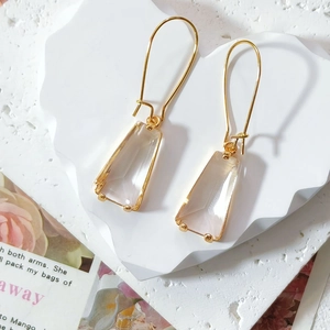 Detail view of elegant gold-tone earrings with long hooks and pink trapezoid crystals