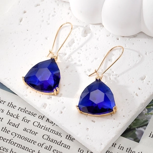 Elegant gold earrings featuring deep blue triangle cut geometric crystals in minimalist hook style