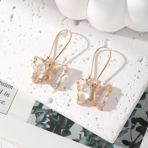 Macro detail of elegant gold butterfly drop earrings with clear crystals and long hooks