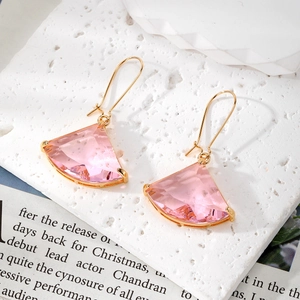Detail of fan-shaped pink crystal earrings with gold hooks on a minimalist white surface