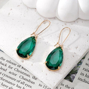 Detail showing elegant teardrop emerald green crystal earrings with gold prong setting