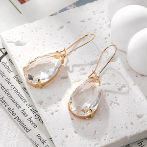 Macro detail of teardrop-shaped crystal earrings with faceted glass and gold plated hooks