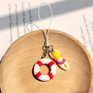 Close-up of mini summer swimmer keychain with red life buoy on light wooden tray