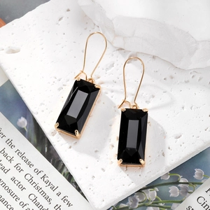 Élégantes boucles d'oreilles dorées avec cristaux noirs taille émeraude sur marbre