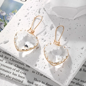 Primer plano de pendientes de corazón de cristal facetado con elegantes ganchos dorados