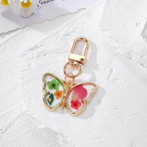 Macro shot of butterfly resin keychain with real dried flowers on white stone