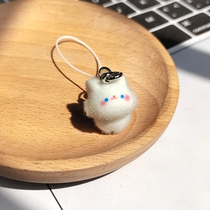 Cute white flocked plush cat keychain with blue eyes on a minimalist wooden tray