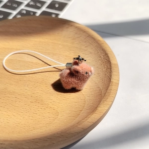 Détail d'un porte-clés cochon rose floqué sur un plateau en bois avec lumière naturelle