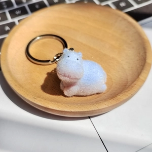 Porte-clés hippopotame floqué bleu avec tête de canard sur plateau en bois