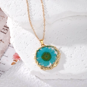 Detail of handmade necklace with blue dried flower in irregular gold resin pendant