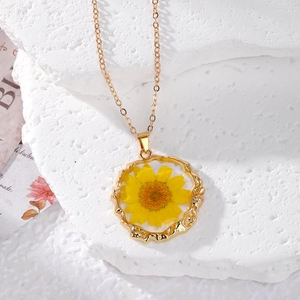 Macro shot of a golden irregular round pendant featuring real dried yellow daisy flowers