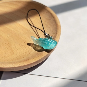 Detailed macro view of a translucent blue polka dot whale shark charm with a black lanyard