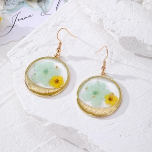 Detailed view of handmade stainless steel earrings with real blue and yellow dried flowers
