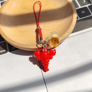Dettaglio del portachiavi con boccale di birra e gambero rosso su vassoio di legno