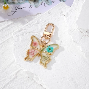 Luminous gold butterfly keychain with real dried flowers and resin daisy pendant
