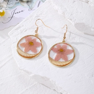 Detail of floral earrings with pink dried flowers and crescent moon in gold frame