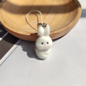 Close-up detail of a white flocked bunny keychain with soft fur texture and metal clasp