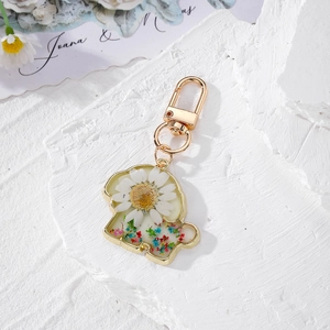 Detailed view of handmade animal-shaped resin keychain with real dried daisy and floral inlay