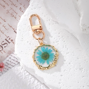 Golden keychain with real blue daisy dried flower in resin on textured stone base