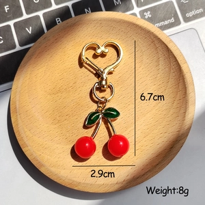 Detail showing red cherry pendant size of 6.7cm with golden heart-shaped keychain