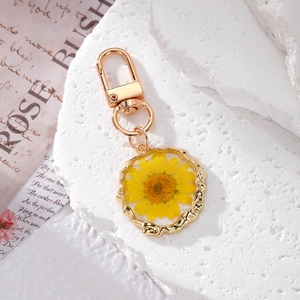 Close-up of yellow dried flower daisy pendant in resin with golden wavy metal frame