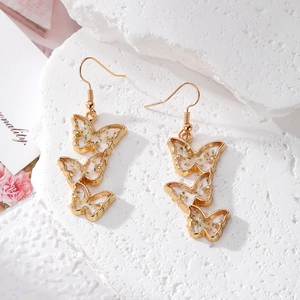 Detailed macro view of golden butterfly earrings with resin-embedded dried flowers