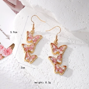 Detailed view of handmade butterfly earrings with real dried flowers in gold resin