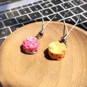 Close-up of realistic resin cheese pendants in pink and orange on a wooden tray