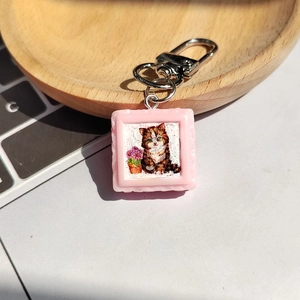 Détail d'un porte-clés photo chat avec cadre rose en relief sur un plateau en bois