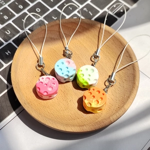 Close-up of four gradient cheese resin charms with porous texture on a wooden tray