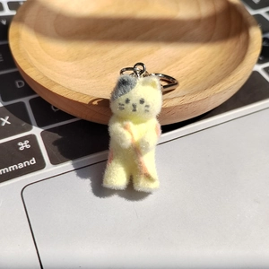 Gros plan d'un porte-clés chat en résine floquée sur un plateau en bois devant un clavier