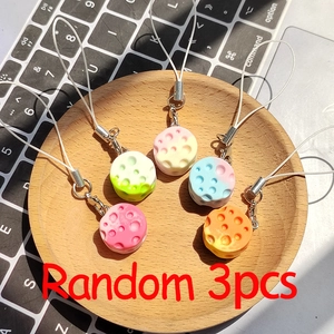 Close-up of three macaron-colored resin cheese charms with silver lobster clasps on a tray