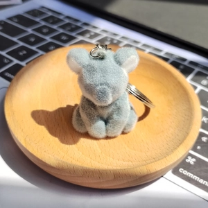 Gros plan d'un porte-clés koala floqué gris sur plateau en bois et ordinateur portable