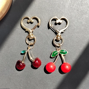 Realistic cherry heart keychains in red resin with gold-tone hardware and green leaves