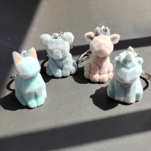 Détail de quatre porte-clés animaux floqués aux couleurs pastel avec anneaux en métal
