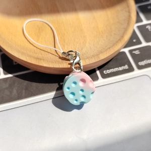 Blue and pink gradient cheese keychain charm with metal lobster clasp on a laptop desk