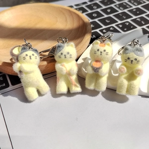 Gros plan de quatre porte-clés chat en résine floquée avec texture douce sur bois
