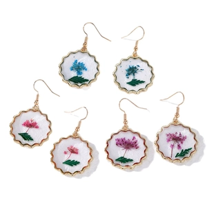 Detailed macro view of handmade dried flower resin earrings with golden wavy frames