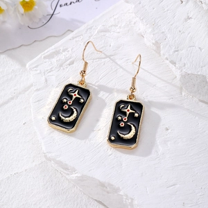 Close-up of alloy tarot earrings featuring golden moon and stars on black enamel drop