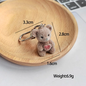 Detailed view of brown flocked bear keychain with red heart and silver metal D-ring buckle
